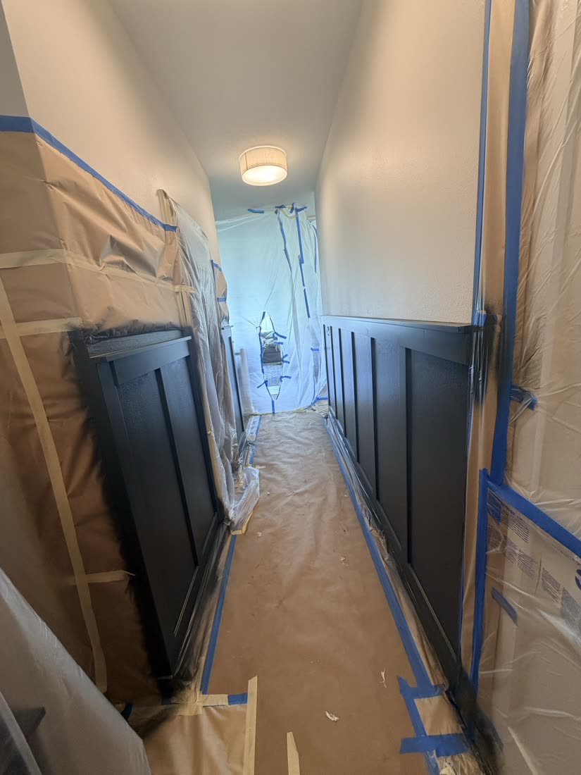 Hallway with dark paneling, masked trim and paper-covered floors