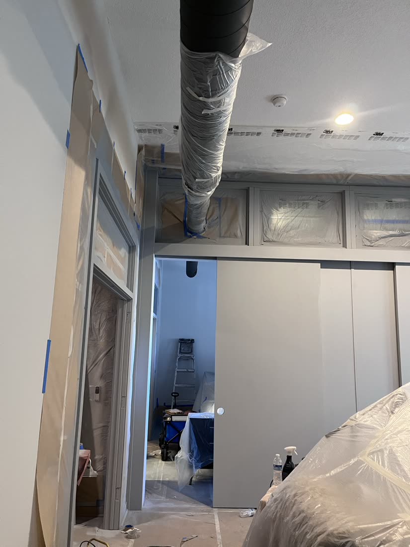 Room with ductwork wrapped in plastic and masked door frames